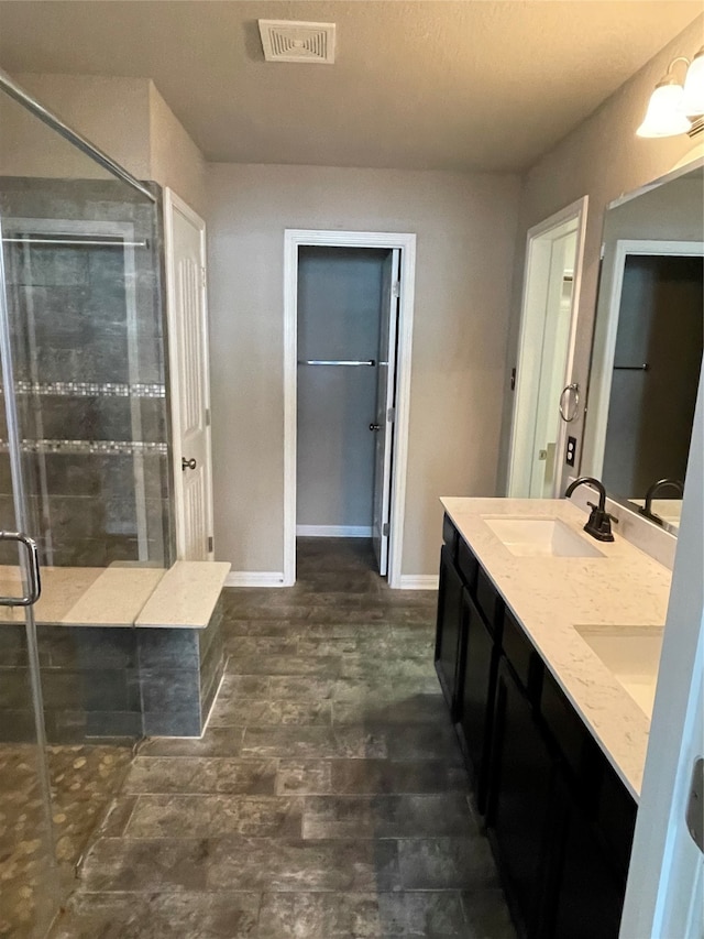 bathroom featuring double sink vanity and a shower with shower door