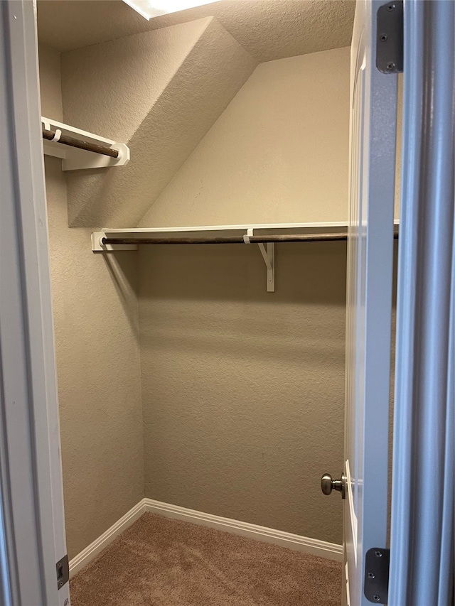 walk in closet featuring lofted ceiling and dark carpet