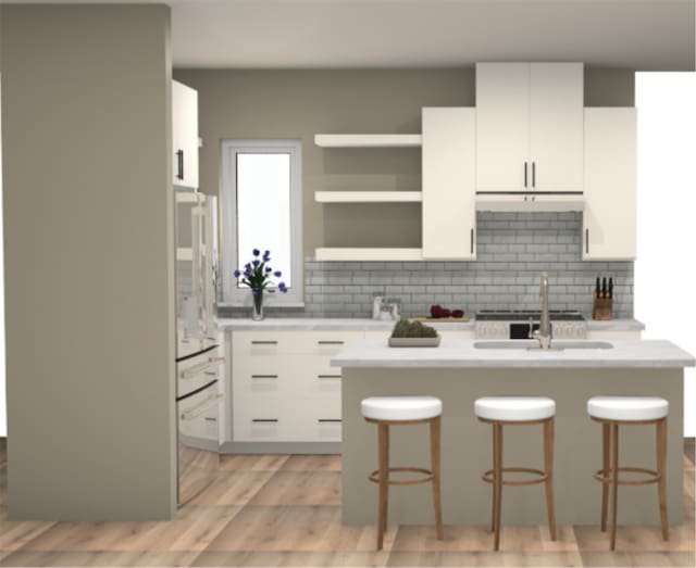 kitchen with white cabinets, a kitchen breakfast bar, backsplash, and light hardwood / wood-style floors