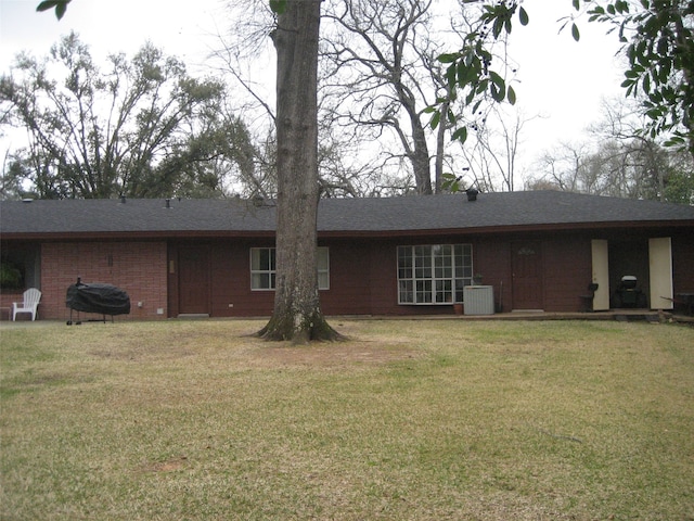 rear view of property with a lawn and central air condition unit