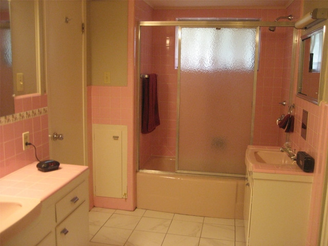 bathroom with tile walls, combined bath / shower with glass door, tasteful backsplash, and vanity