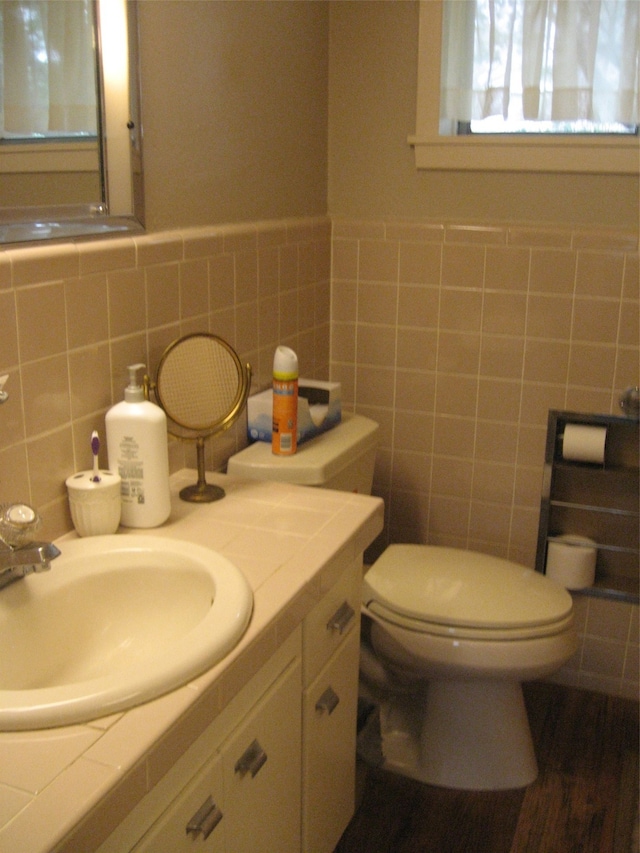 bathroom with tile walls, hardwood / wood-style floors, backsplash, toilet, and vanity