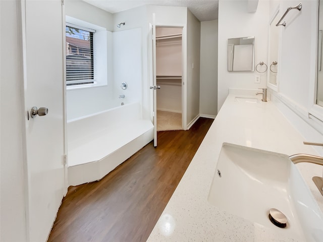 bathroom with wood-type flooring, vanity, a textured ceiling, and a tub