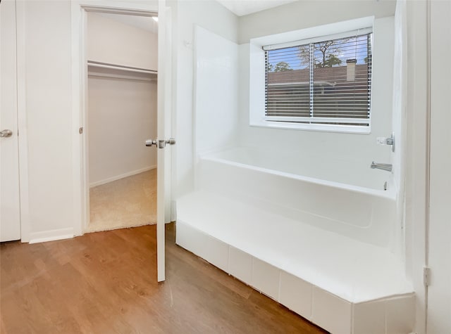 bathroom featuring a tub to relax in and wood-type flooring