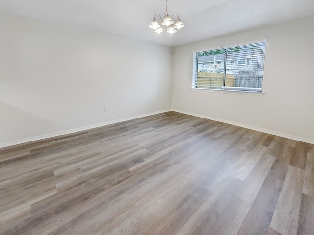 empty room featuring a notable chandelier and light hardwood / wood-style flooring