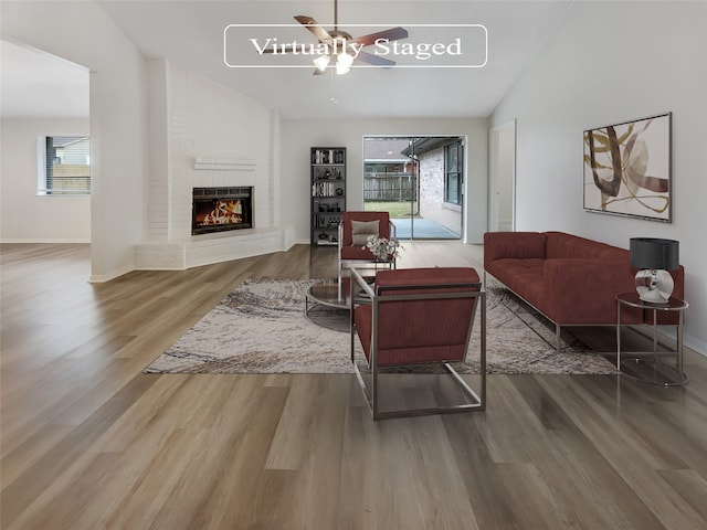 living room with a fireplace, ceiling fan, plenty of natural light, and hardwood / wood-style floors