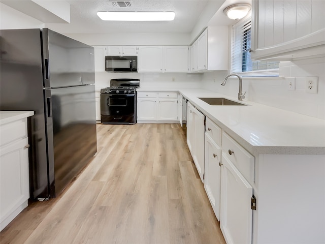 kitchen featuring black appliances, white cabinets, sink, and light hardwood / wood-style flooring