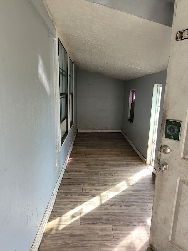 corridor featuring a textured ceiling and dark hardwood / wood-style flooring