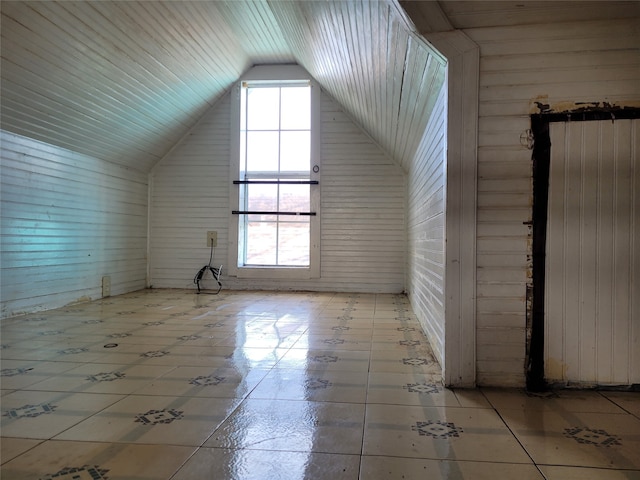 bonus room with light tile floors, wood walls, and vaulted ceiling