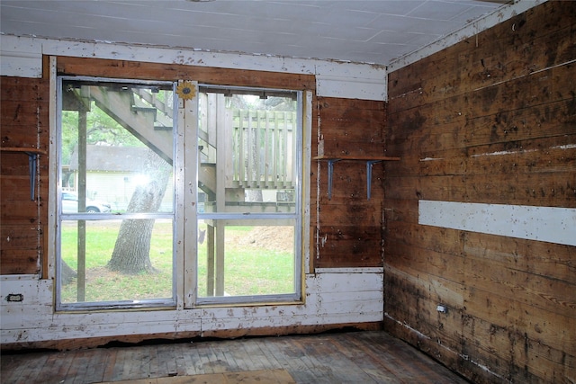 unfurnished room with dark hardwood / wood-style floors, a wealth of natural light, and wood walls