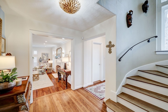 foyer entrance featuring ornamental molding, a textured ceiling, and light wood-type flooring