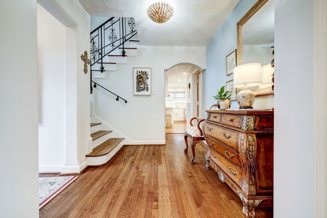 hallway featuring light wood-type flooring and a textured ceiling