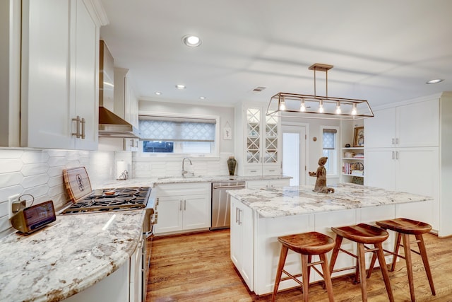 kitchen featuring sink, hanging light fixtures, a kitchen island, white cabinets, and appliances with stainless steel finishes