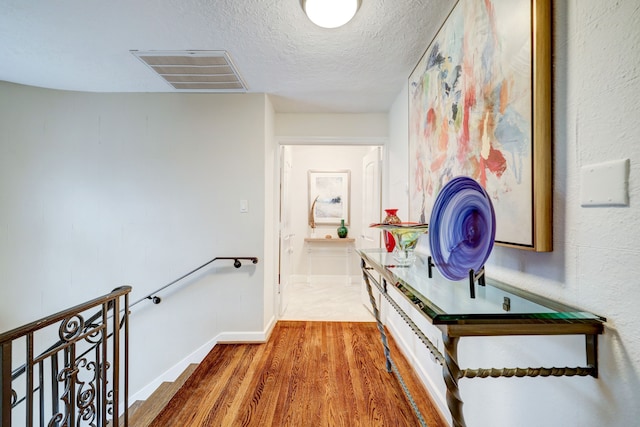 hallway featuring hardwood / wood-style floors and a textured ceiling