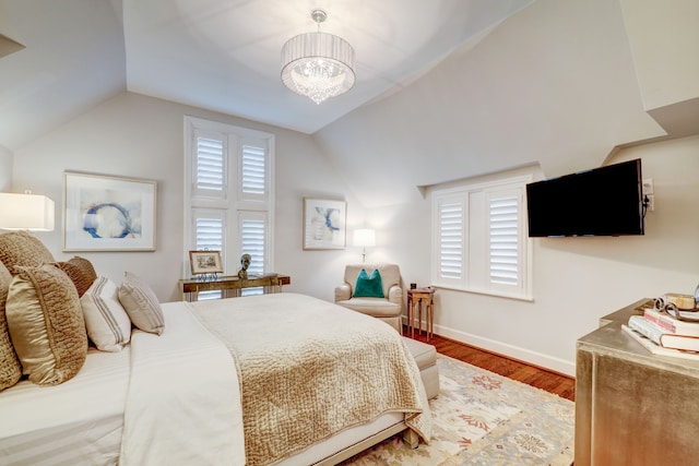 bedroom with wood-type flooring, an inviting chandelier, and lofted ceiling