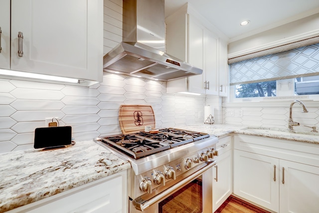 kitchen featuring sink, backsplash, high end stainless steel range oven, and wall chimney range hood