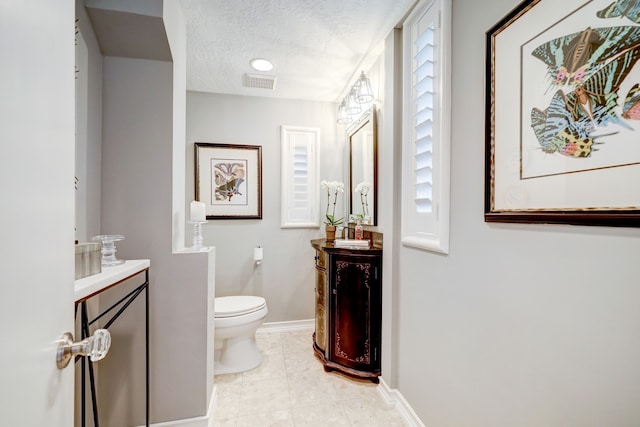 bathroom featuring vanity, tile patterned floors, a textured ceiling, and toilet