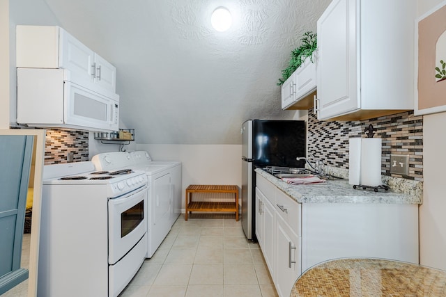 kitchen with lofted ceiling, sink, independent washer and dryer, light tile patterned floors, and white cabinetry