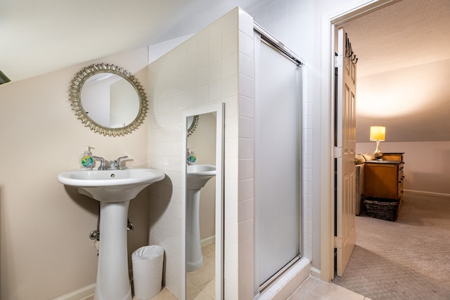 bathroom with a shower with door, a textured ceiling, and vaulted ceiling