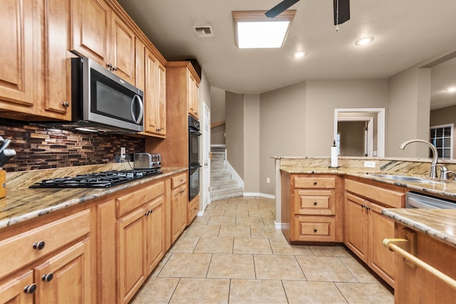 kitchen featuring ceiling fan, light tile floors, light stone countertops, black appliances, and tasteful backsplash