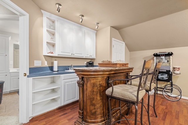 bar featuring dark tile flooring, white cabinetry, and lofted ceiling