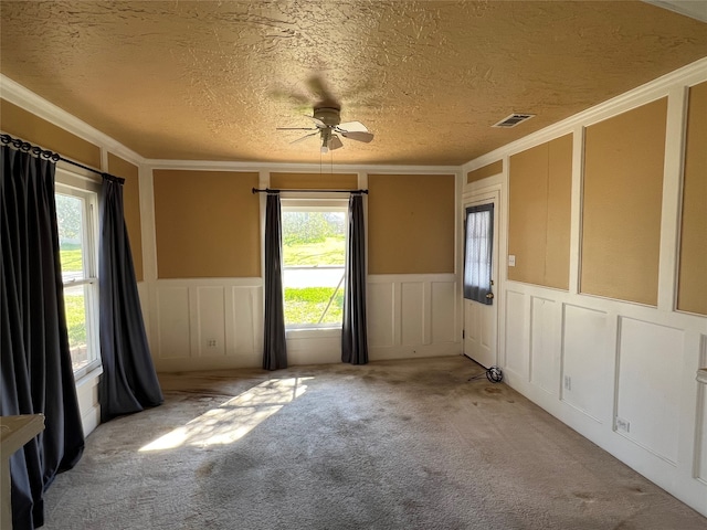 carpeted empty room with a textured ceiling, ceiling fan, and ornamental molding