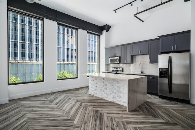 kitchen with a kitchen island, sink, parquet flooring, and stainless steel appliances