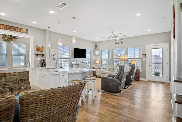 living room with light hardwood / wood-style floors, ceiling fan, and sink