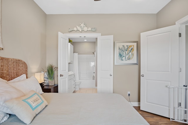 bedroom with ensuite bathroom and hardwood / wood-style floors