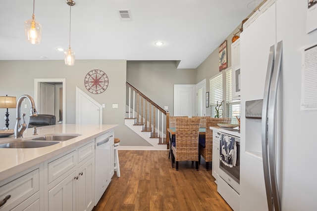 kitchen with refrigerator with ice dispenser, wood-type flooring, white cabinets, range, and sink