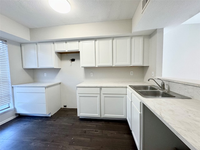 kitchen with a textured ceiling, dark wood-type flooring, white cabinetry, and sink