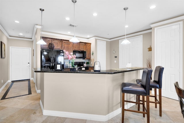 kitchen featuring dark stone countertops, hanging light fixtures, black appliances, and a kitchen breakfast bar