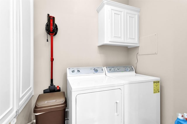 laundry room featuring separate washer and dryer and cabinets