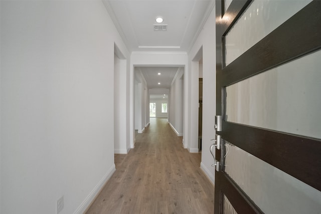 corridor featuring light wood-type flooring and crown molding