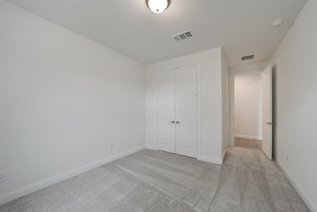 unfurnished bedroom featuring a closet and light colored carpet