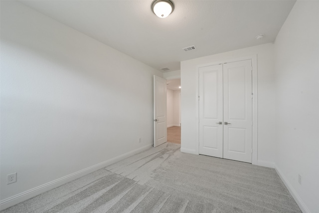 unfurnished bedroom featuring light carpet and a closet