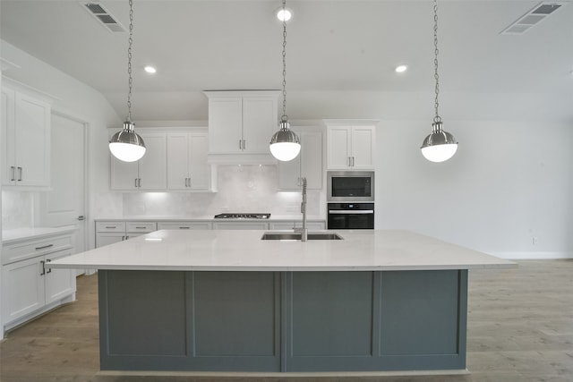 kitchen with a large island, light wood-type flooring, pendant lighting, sink, and white cabinetry