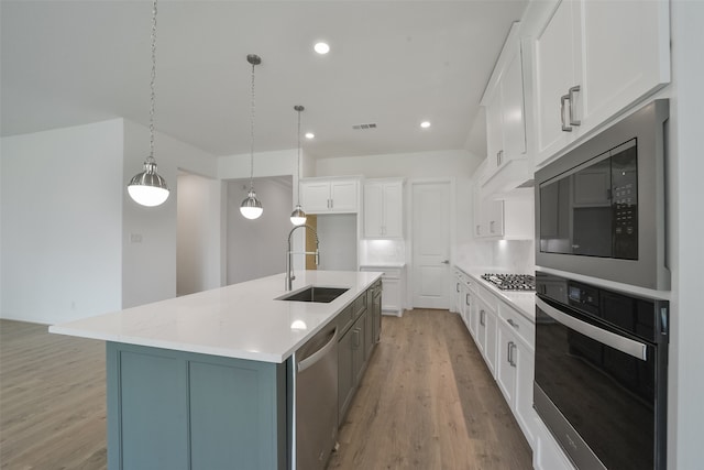 kitchen featuring a large island with sink, sink, white cabinets, hanging light fixtures, and black appliances