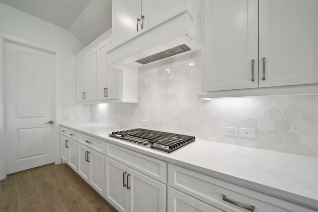 kitchen with dark wood-type flooring, tasteful backsplash, stainless steel gas stovetop, white cabinetry, and custom range hood