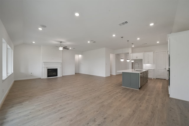 unfurnished living room featuring light hardwood / wood-style floors, sink, and ceiling fan