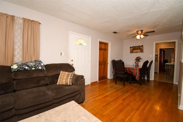 living room with ceiling fan, hardwood / wood-style flooring, and a textured ceiling