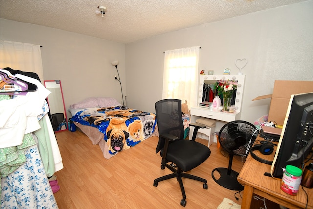 bedroom with a textured ceiling and light wood-type flooring