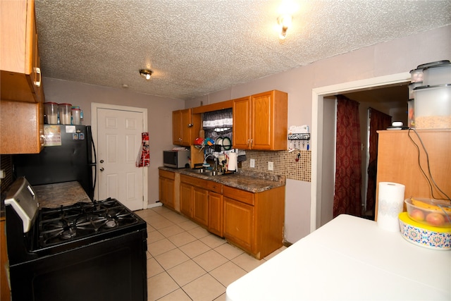 kitchen with light tile flooring, black fridge, a textured ceiling, backsplash, and gas range oven