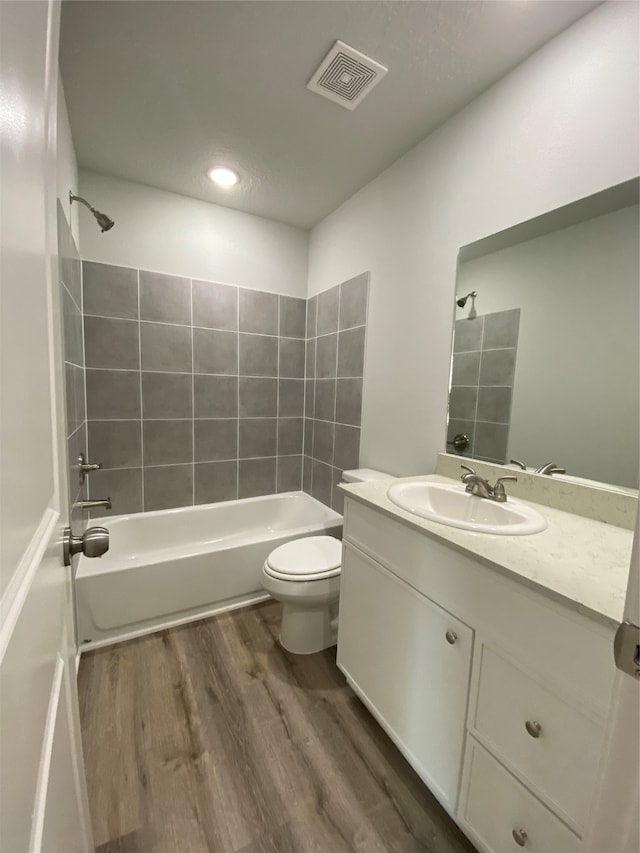 bathroom with wood finished floors, toilet,  shower combination, vanity, and recessed lighting