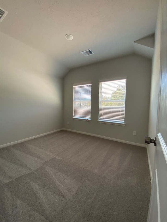 carpeted spare room featuring lofted ceiling and baseboards