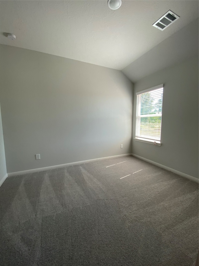 carpeted spare room featuring lofted ceiling, baseboards, and a smoke detector