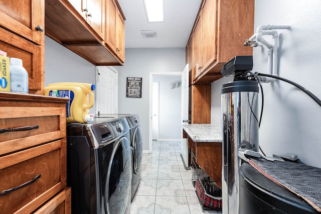 laundry area with washer and clothes dryer, light tile flooring, and cabinets