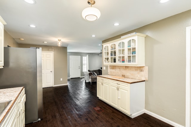 kitchen with stainless steel fridge, sink, light stone counters, dark wood-type flooring, and tasteful backsplash