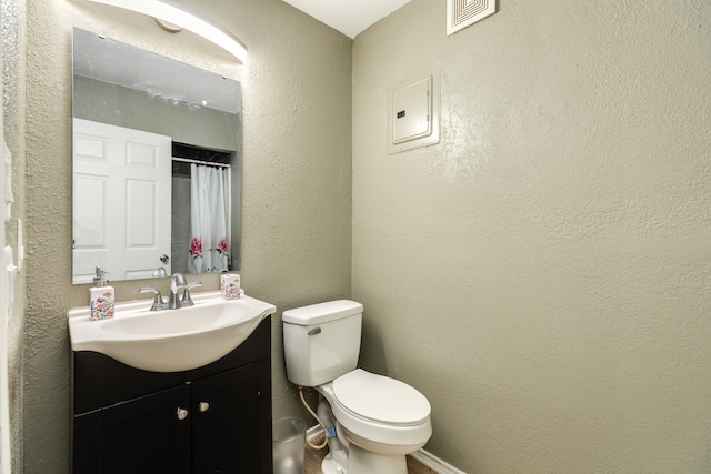 bathroom with toilet and vanity with extensive cabinet space