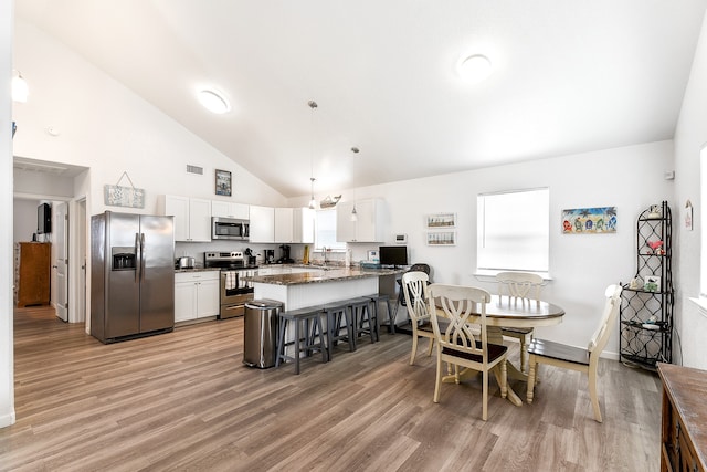 dining area with sink, light wood-type flooring, high vaulted ceiling, and a chandelier